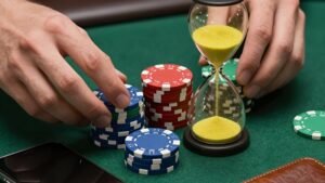 Hands organizing poker chips by a smartphone and hourglass for managing poker bankroll timings